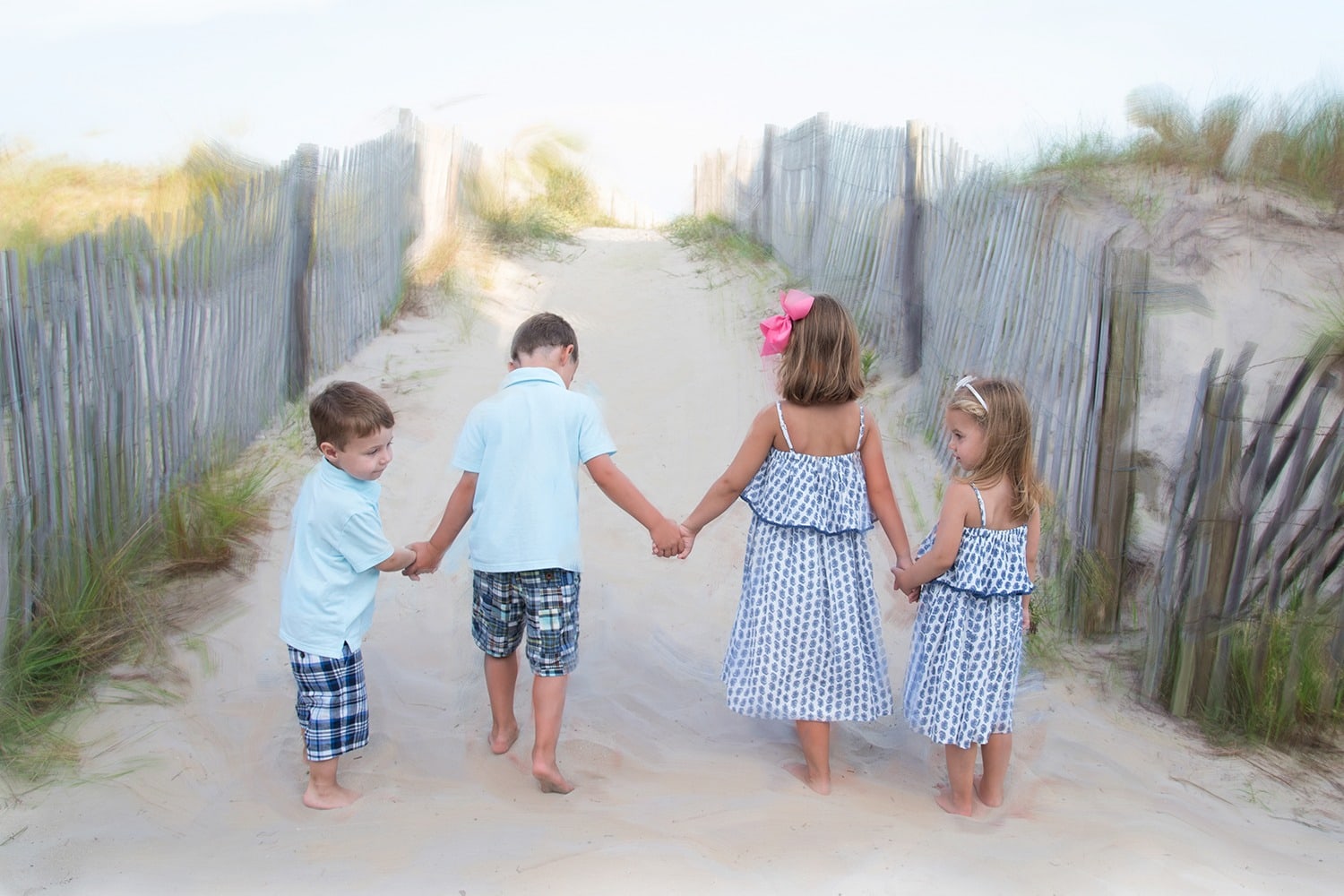 Children holding hand while walking on beach in matching outfits