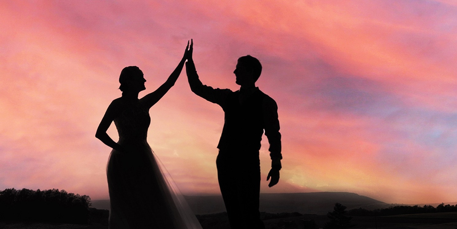 married couple giving a high five in silhouette 